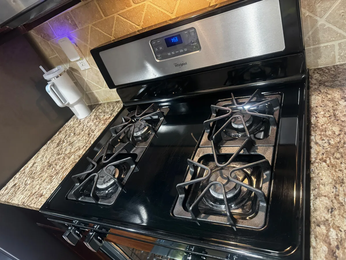 Black gas range with clean cast iron grates and a wiped down stovetop