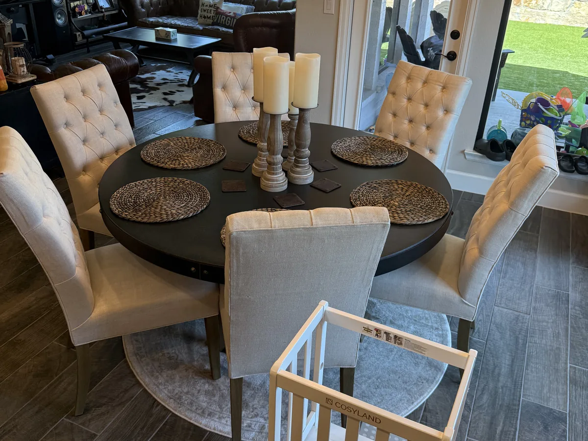Round dining table with upholstered chairs and candles after a house cleaning