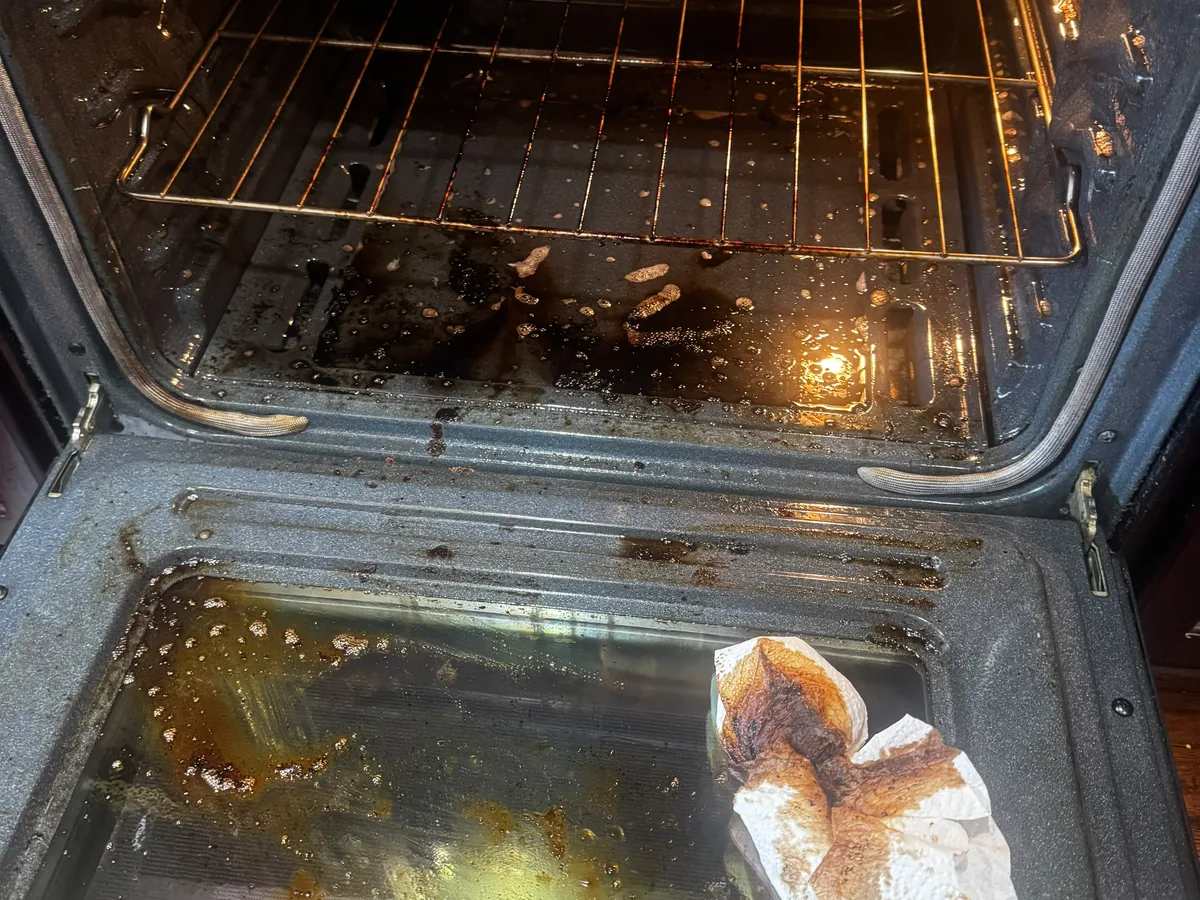 Oven interior with grease on the door glass and food residue on the racks
