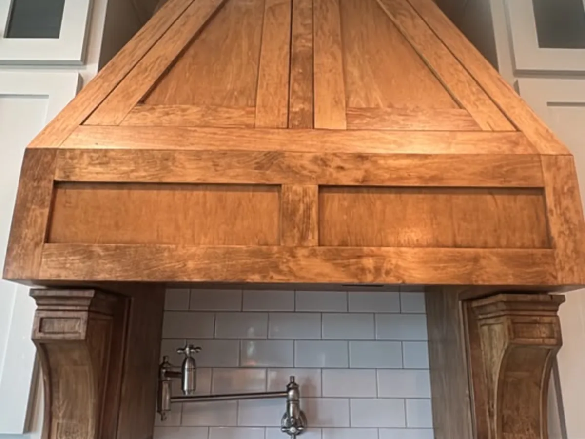 Wood range hood and white subway tile backsplash wiped down and clean