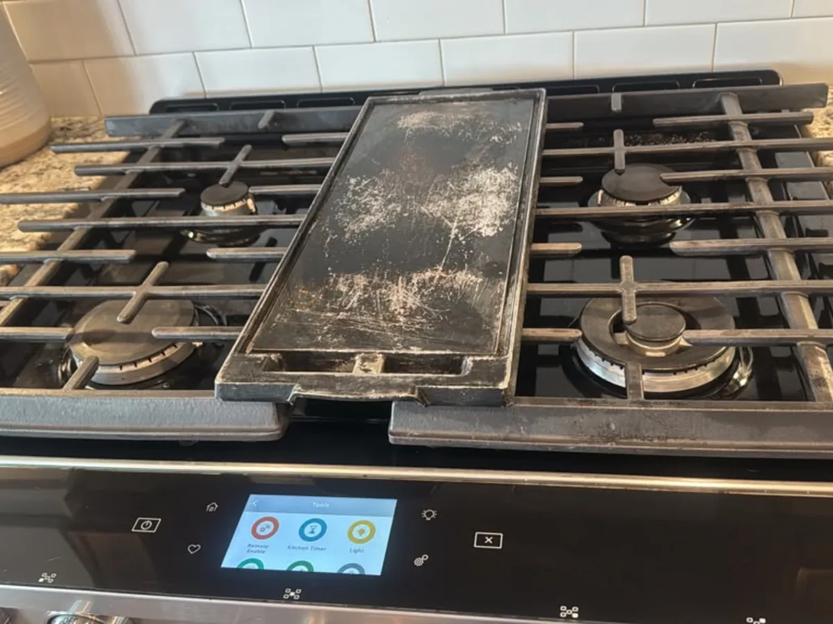 Gas cooktop with a center griddle plate and cast iron grates