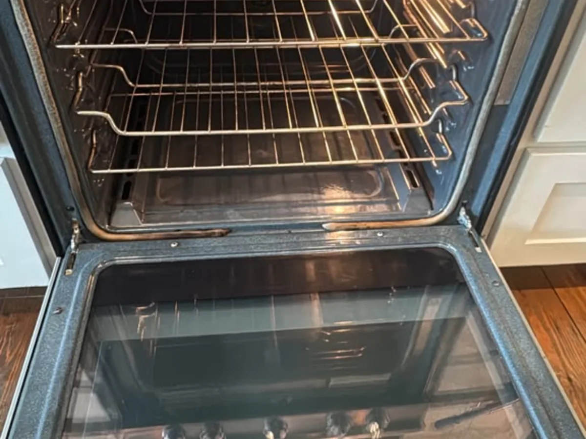 Clean oven interior with bare racks and a wiped down glass door after a deep cleaning