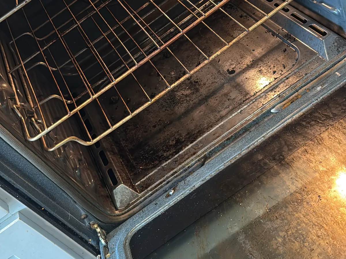 Oven interior with heavy baked on carbon and grease across the back wall and racks