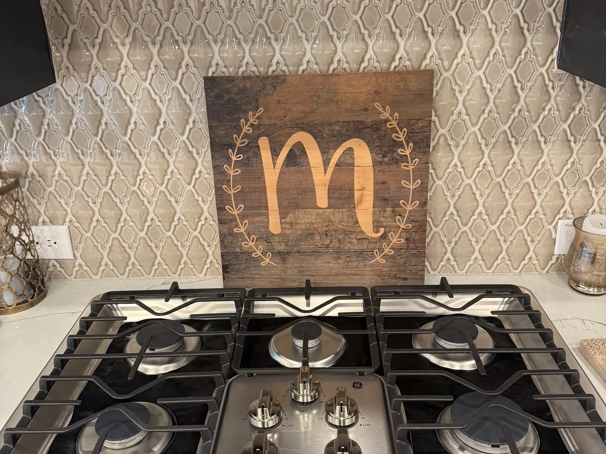 Stainless steel gas cooktop with clean grates below a patterned tile backsplash